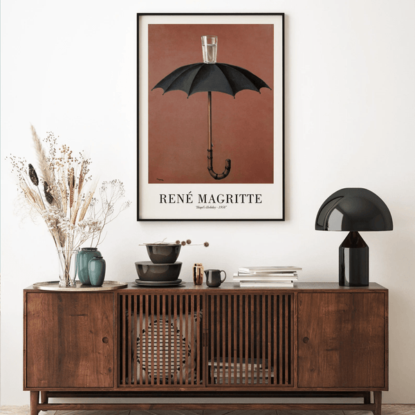 René Magritte plakat med sort paraply og glas vand ovenpå mod brun baggrund – surrealistisk kunstværk.